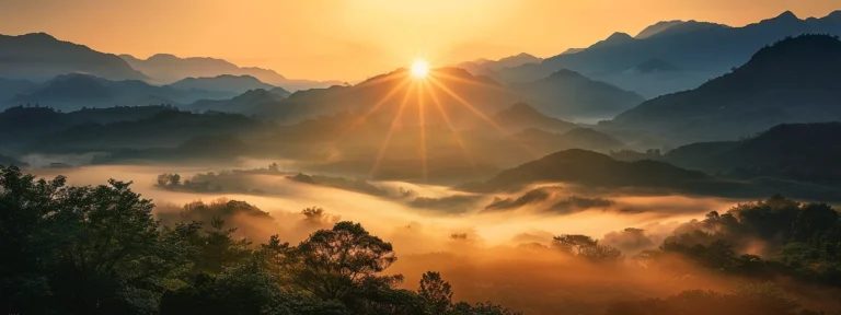 a breathtaking sunrise casts a warm golden glow over a serene fog-covered valley, with majestic mountains in the background emerging from the mist.